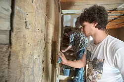 Der freiwillige Helfer Emil verputzt die Wand eines Fachwerkhauses. - &copy; Thomas Frey/dpa