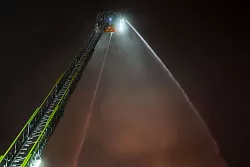 Von einer Drehleiter versuchte die Feuerwehr, den Brand zu löschen. - © Christoph Reichwein/dpa