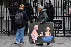 Ein Künstler geht in London mit einem Gemälde von Trump, Selenskyj und Putin am Tag der Ukraine-Gespräche vor den Toren der Downing Street 10 entlang. - © Frank Augstein/AP/dpa