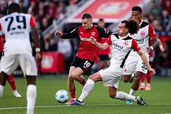 Für den Ex-Leverkusener Florian Wirtz (M) kommt es am Mittwoch zum Wiedersehen mit Eintracht Frankfurt um Arthur Theate (r). (Archivbild) - © Marius Becker/dpa