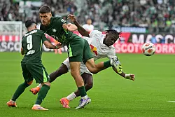 Kaum zu stoppen: Leipzigs Torschütze Johan Bakayoko (r) wird von den Wolfsburgern Joakim Maehle und Mohammed Amoura bedrängt. - © Swen Pförtner/dpa