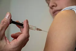 Eine Gynäkologin impft eine Jugendliche gegen HPV. (Archivbild) - © Stefan Puchner/dpa