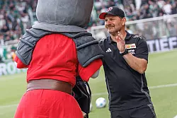 Union-Trainer Steffen Baumgart hat Zeit für einen Handshake mit dem Club-Maskottchen. - © Andreas Gora/dpa