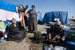 Frauen bereiten in einem provisorischen Zeltlager am Stra&szlig;enrand in Kirikhan Essen zu. - &copy; Boris Roessler/dpa