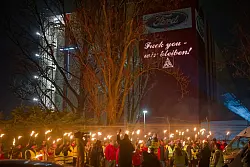 Ein Fackelmeer protestierender Ford-Mitarbeiter vor einem provokanten Schriftzug an einer Halle des Autobauers: «Fuck you - wir bleiben». - © Henning Kaiser/dpa