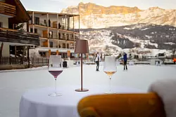 Darauf ein Prost: In der Ferne leuchten die Berge, während sich einige Mutige selbst für ein Tänzchen aufs Eis wagen. - © Manuel Glira/Alta Badia/dpa-tmn