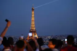 Paris im Sommer 2024 - besonders beliebt: Touristen fotografieren den Eiffelturm mit den Olympischen Ringen von der Terrasse des Triumphbogens. (Archivbild) - © Jan Woitas/dpa