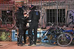 Polizisten nehmen die Personalien einer Person auf. - © Robert Michael/dpa