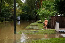 Eine Frau spaziert mit ihrem Hund durch das Hochwasser im Vorort Holloways Beach in Cairns. - &copy; Joshua Prieto/AAP/dpa