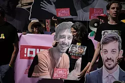 Demonstranten halten bei einem Protest gegen die Offensive in der Stadt Gaza Fotos von Geiseln. - &copy; Mahmoud Illean/AP/dpa