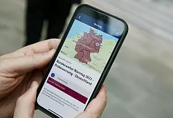 Ein Mitarbeiter des Bundeskanzleramts h&auml;lt sein Mobiltelefon in der Hand. - &copy; Wolfgang Kumm/dpa