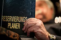 Altmodisch? Ein Gastronom schaut in sein Reservierungsbuch. - © Christoph Reichwein/dpa