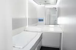 In den Schlafkabinen wartet ein frisch bezogenes Bett, ein Tisch sowie ein Touchscreen, mit dem die Beleuchtung gesteuert, der Wecker gestellt oder Musik ausgewählt werden kann. - © Flughafen Stuttgart GmbH/dpa-tmn