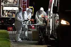 Mitarbeiter der Spurensicherung stehen nach dem Fund der Leiche an ihren Einsatzfahrzeugen. - © Swen Pförtner/dpa