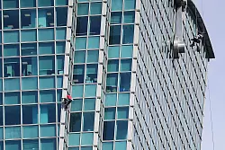 Schaulustige beobachteten Alex Honnold nicht nur vom Boden aus - auch hinter den B&uuml;rofenstern wurde der Extremsportler angefeuert. - &copy; ChiangYing-ying/AP/dpa