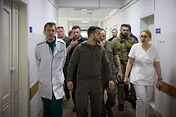Pr&auml;sident Selenskyj (M) besucht ein Krankenhaus in dem von den &Uuml;berschwemmungen betroffenen Gebiet von Cherson. - &copy; Uncredited/Ukrainian Presidential Press Office/AP/dpa