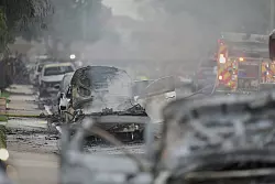 Einsatzkräfte fahren an beschädigten Fahrzeugen am Schauplatz des Absturzes eines Kleinflugzeugs in einem Stadtviertel von San Diego vorbei. - © Gregory Bull/AP/dpa