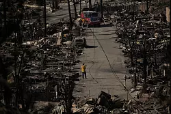 Einsatzteams durchkämmen die ausgebrannten Gebiete. - © Jae C. Hong/AP/dpa
