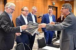 Zum Beginn der Tarifverhandlungen in der Stahlindustrie &uuml;berreicht der Verhandlungsf&uuml;hrer der IG Metall, Knut Giesler, zwei T-Shirts an den Verhandlungsf&uuml;hrer der Arbeitgeber, Reiner Blaschek (2.v.l), sowie den Gesch&auml;ftsf&uuml;hrer des Arbeitgeberverbandes Stahl, Gerhard Erdmann (l). - &copy; Federico Gambarini/dpa