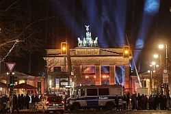 Silvester in Berlin: Polizeiwagen stehen vorm angestrahlten Brandenburger Tor. - © Annette Riedl/dpa