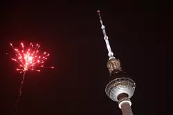Eine Rakete explodiert in der Silvesternacht in der Nähe des Berliner Fernsehturms. - © Sebastian Christoph Gollnow/dpa