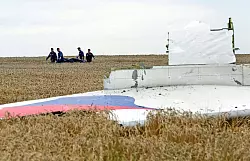 Einsatzkräfte transportieren eine Trage mit einem Leichensack durch ein Getreidefeld an der Absturzstelle der Boeing 777, die als Flug MH17 der Malaysia Airlines etwa 100 km östlich von Donezk abstürzte. - © Anastasia Vlasova/EPA/dpa