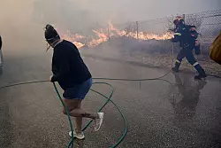 Bewohner und Feuerwehrleute bekämpfen die Flammen. - © Marios Lolos/XinHua/dpa