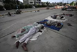 Arbeiter schlafen am Stra&szlig;enrand an einem hei&szlig;en Sommermorgen in Karatschi. - &copy; Fareed Khan/AP/dpa