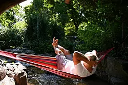 Ein Mann schaukelt im Berliner in einer Hängematte über dem Wasser. - © Katharina Kausche/dpa