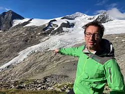Florian Jurgeit vom Nationalpark Hohe Tauern zeigt von der Neuen Prager Hütte auf den inzwischen weit entfernten Gletscher. - © Sabine Dobel/dpa
