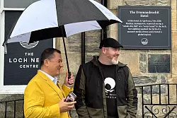 Paul Nixon (l) vom Loch Ness Centre und der Projektleiter Alan McKenna neben der Plakette, die an eine ber&uuml;hmte Nessie-Sichtung im Jahr 1933 erinnert. - &copy; Benedikt von Imhoff/dpa