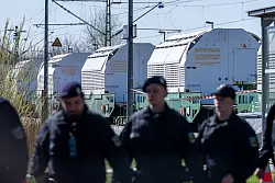 Polizisten sichern einen Zug mit Castor-Behältern ab. - © Armin Weigel/dpa