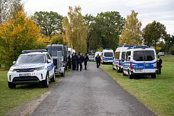 Polizeiautos stehen auf einer Wiese in Tauche. - © Christophe Gateau/dpa