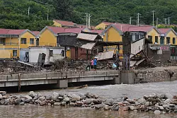 Dorfbewohner versammeln sich in der N&auml;he einer Br&uuml;cke, die nach schweren Regenf&auml;llen im Bezirk Miyun am Stadtrand von Peking &uuml;berflutet wurde. - &copy; Andy Wong/AP/dpa