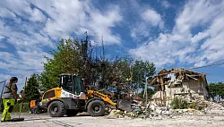 Mit einem Radlader werden Trümmer beseitigt. - © Stefan Puchner/dpa