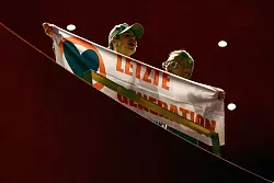 Ein Aktivist der Letzten Generation zeigt w&auml;hrend der Podiusmdiskussion mit Kanzler Scholz ein Transparent. - &copy; Kai Pfaffenbach/REUTERS POOL/dpa