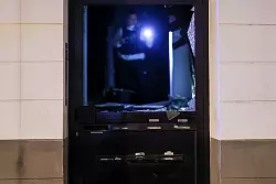 Ein Beamter untersucht Spuren im Hausflur. - © Christoph Reichwein/dpa