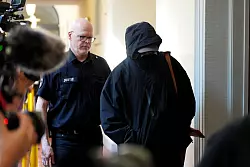 Ein Angeklagter wird von einem Polizisten zum Gerichtssaal begleitet. - © Marcus Brandt/dpa