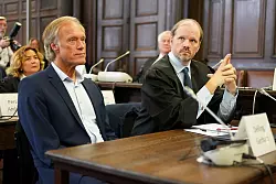 Gerhard Delling, gekleidet im dunklen Anzug ohne Krawatte, setzte sich gleich nach Betreten des Gerichtssaals neben seinen Anwalt. - © Marcus Brandt/Pool-dpa/dpa