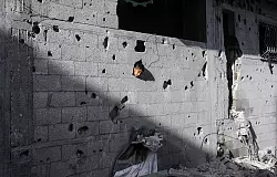 Ein palästinensisches Kind schaut aus einem Loch in einem Gebäude in Chan Junis, das durch einen israelischen Luftangriff beschädigt wurde - © Abed Rahim Khatib/dpa