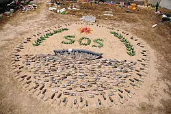 Plastikabfälle bilden ein überdimensionales SOS in einem Garten in Tunesien. - © Simon Kremer/dpa