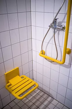 Duschen ohne Stolperfallen: Ein an der Wand montierter Klappsitz macht die Körperpflege auch für ältere Menschen sicherer. - © Ole Spata/dpa-tmn