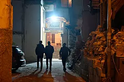 Gäste passieren Trümmer auf dem Weg in das Meyhane Serenat. - © Anne Pollmann/dpa