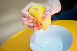 Schritt 2: Zitrone mit der Hand auspressen - der Saft spritzt kontrolliert in die Schale. - © Christin Klose/dpa-tmn