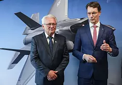 Papperger und Wüst vor einem Bild des F-35-Flugzeugs. Ende nächsten Jahres soll das erste Rumpfmittelteil dieses Tarnkappenbombers in Weeze fertig sein. - © Oliver Berg/dpa