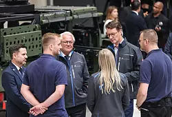 Rheinmetall-Chef Armin Papperger (Dritter von links) und NRW-Ministerpräsident Hendrik Wüst (zweiter von rechts) bei einem Rundgang durch die F-35-Produktionsanlage. - © Oliver Berg/dpa