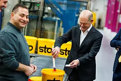 Kanzler Scholz macht beim Baustoffhersteller Sto eine Farbenprobe. - © Philipp von Ditfurth/dpa