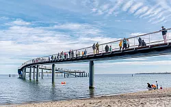 Die Seebrücke in Timmendorfer Strand führt in einem weiten Bogen übers Wasser. - © Markus Scholz/dpa/dpa-tmn