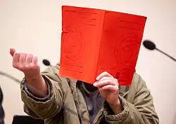 Der Angeklagte verdeckte sein Gesicht zum Prozessauftakt zun&auml;chst mit einer Mappe. - &copy; Peter Kneffel/dpa