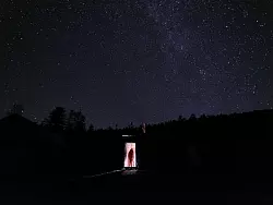 Hao-Cheng Yu geht unter einem spektakulären Sternenhimmel in die Hütte, die er während seiner Forschungen bewohnte. - © Jiayi Wang/Nature/dpa